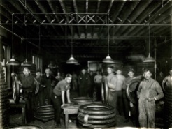 Workers in a large workroom inspecting newly made tires.