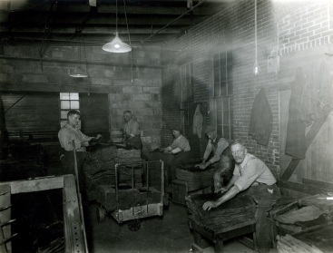 Several employees at the Mansfield Tire Co. inspecting crude rubber.