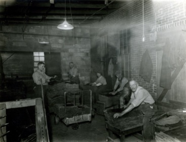 Several employees at the Mansfield Tire Co. inspecting crude rubber.