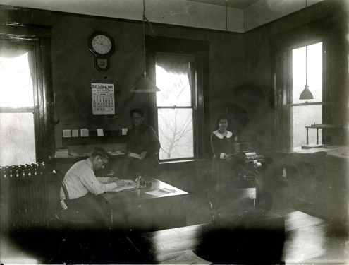 Three office employees working in the office of the Mansfield Tire Co. The calendar reads November 1921.